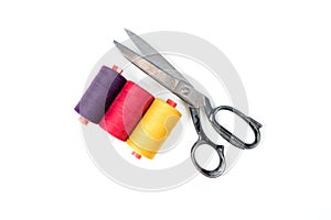 Colored sewing thread coils with old metal scissors on white background