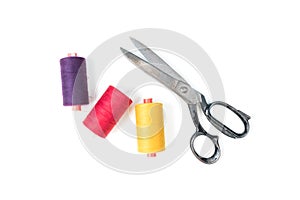 Colored sewing thread coils with old metal scissors on white background