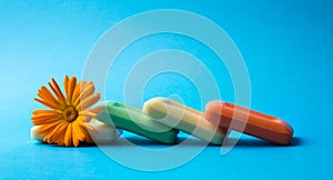 Colored soap bars with fresh marigold flower isolated on blue background