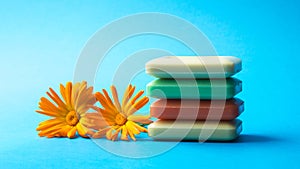 Colored soap bars with fresh marigold flowers isolated on blue background