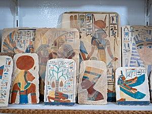 Colored stone tablets in a gift shop featuring Egyptian-themed drawings of ancient gods. Luxor, Egypt