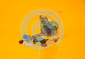 colored stones in glass in jar in bucket on orange background