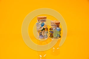 colored stones in glass in jar in bucket on orange background