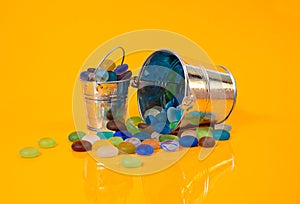 colored stones in glass in jar in bucket on orange background