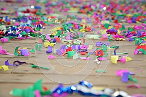 Colored streamers confetti scattered on the wooden plank floor. Happy party background.