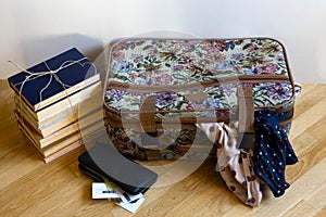 A colored suitcase for a trip, with two scarves sticking out of it,