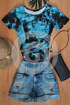 Colored t-shirt and women`s jean shorts on wood