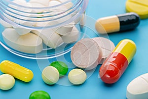 Colored tablets, capsules for treatment. Blue background, studio shot.