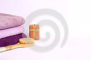 Colored terry towels, a wooden brush for dry massage, soap on a white background