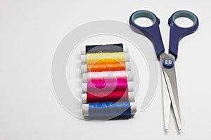 Colored thread and scissors isolated on white background.