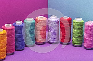 Colored threads on a bobbin on  colored background