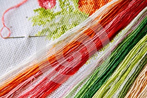 Colored threads for embroidery on a embroidered canvas.