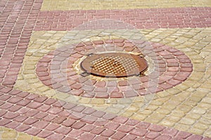 Colored tiles around the sewer hatch in the park