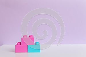 Colored toy bricks on purple background with place for your content