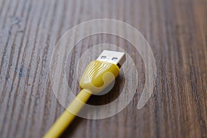 Colored USB type cable staying on dark wooden table.