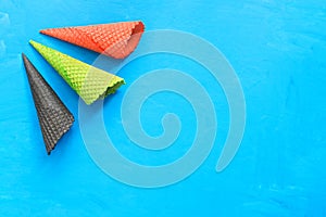 Colored waffle cones for ice cream on a blue painted background. Top view, flat lay, copy space