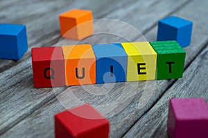 Colored wooden cubes with letters. the word quiet is displayed, abstract illustration