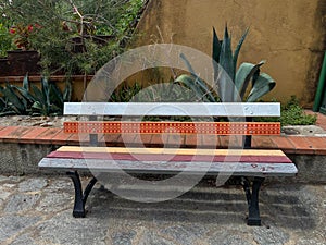 Colored wooden park bench in front of house facade with plantings