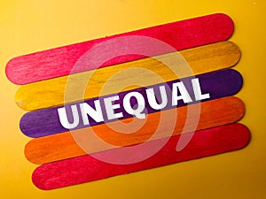 Colored wooden stick with the word UNEQUAL