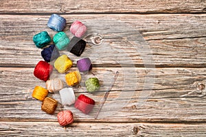 Colored yarn spools and a crochet needle on a wooden background