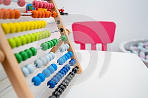 Colorful Abacus on Table with Pink Chairs and Ball Pool in Background, Modern Nursery
