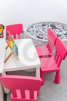 Colorful Abacus on Table with Pink Chairs and Ball Pool in Background, Modern Nursery