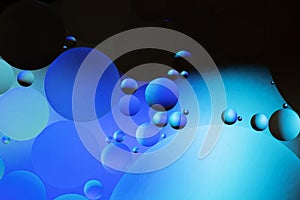 Colorful abstract background. Blue black circles and oil bubbles in the water. Close up. Macro abstraction. Rainbow oil pattern