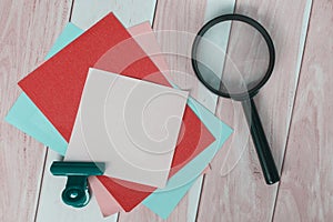 Colorful adhesive paper with magnifying glass on wooden desk.