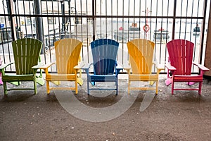 Colorful adirondack chairs against a steel fence in a ferry terminal