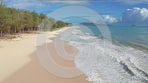 Colorful Aerial View of tropical beach with turquoise blue ocean water and waves lapping on hidden white sand beach