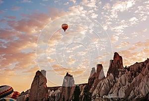 Colorful air balloons fly up into the sky at sunrise among a beautiful rocky landscape. Cappadocia Turkey.