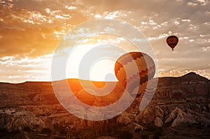 Colorful air balloons fly up into the sky at sunrise among a beautiful rocky landscape. Cappadocia Turkey.