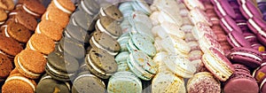 Colorful almond cookies in a gift box and marshmallows in a coffee Cup on a wooden table. Sweet pasta and flowers. Close up.