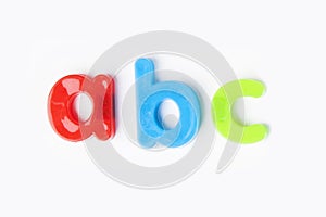 Colorful alphabet magnets spell `a b c` over white background