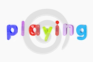 Colorful alphabet magnets spelling `playing` over white background