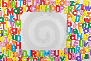 Colorful alphabet magnets on whiteboard framing copy space