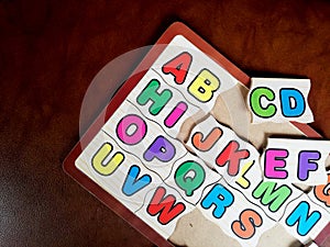 Colorful alphabet puzzle for the kids,isolated on brown background