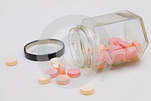 Colorful antacid tablets spilling out of glass bottle