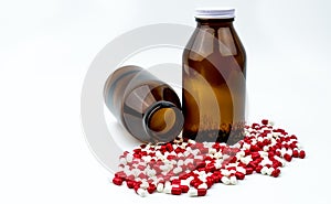 Colorful of antibiotic capsules pills with two amber glass bottles on white background.