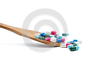 Colorful of antibiotics capsule pills in wooden spoon are spilling on white background with copy space. Antibiotic drug use with r