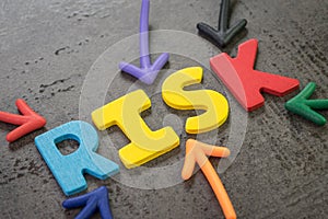 Colorful arrows pointing to the word RISK at the center of black chalkboard wall, business or investment risk, result in