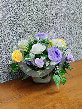 Colorful artificial flower on the table near the wall.