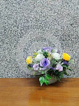 Colorful artificial flower on the table near the wall.