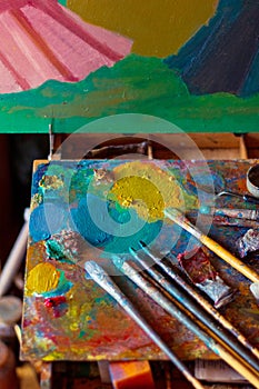 Colorful artist's palette with pastel and oil brushes in art studio