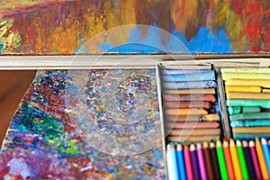 Colorful artist palette with pastel and oil brushes in art studio