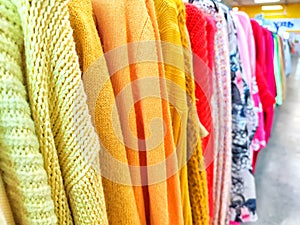 Colorful Assortment of Knitted Sweaters on Display in a Bright Clothing Store. Variety of colorful sweaters hanging on a