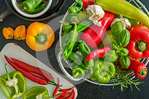 a colorful assortment of peppers, hot peppers and chili, decorated with various assesoires on a wooden table.