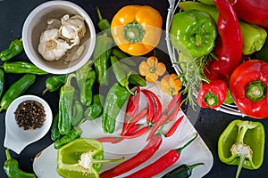 a colorful assortment of peppers, hot peppers and chili, decorated with various assesoires on a wooden table.