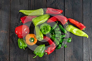 a colorful assortment of peppers, hot peppers and chili, decorated with various assesoires on a wooden table.