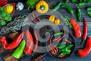 a colorful assortment of peppers, hot peppers and chili, decorated with various assesoires on a wooden table.